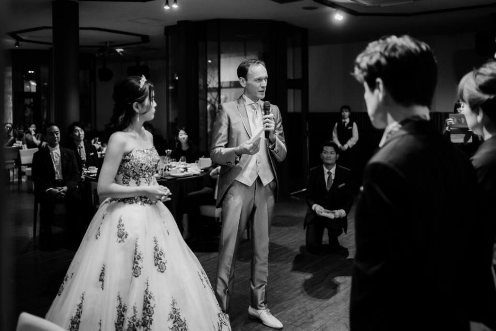 lack-and-white photograph of the groom giving a speech during an elegant wedding reception in Japan.