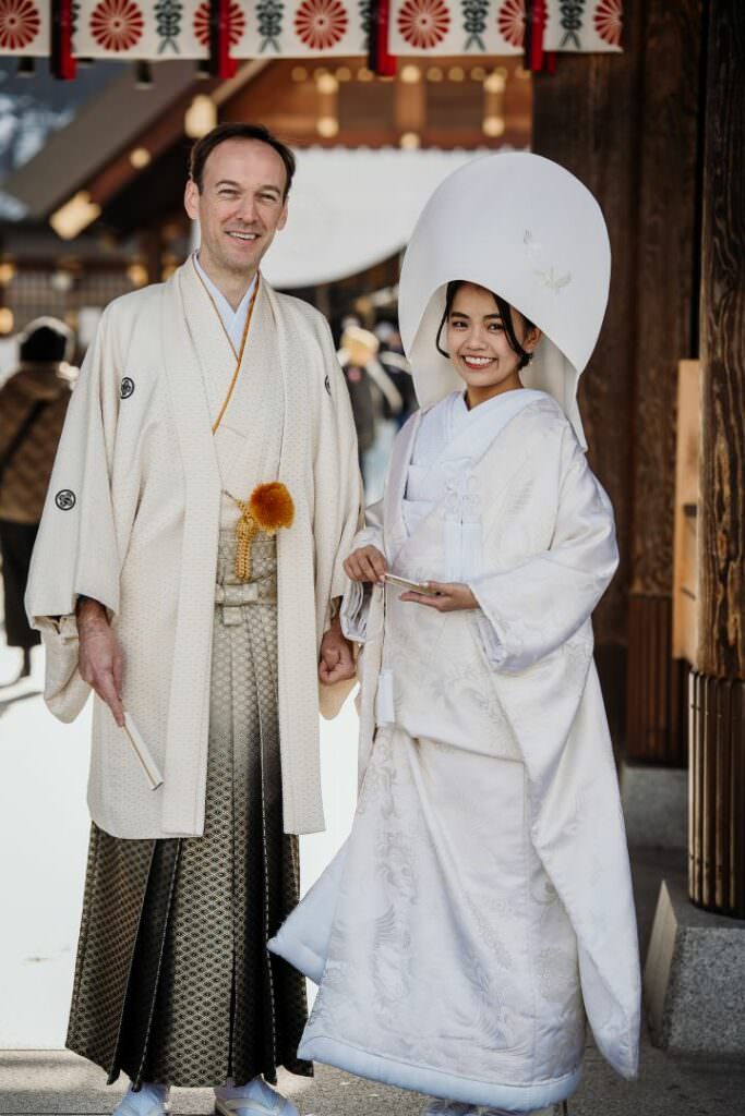 Elegant wedding couple at the entrance of Hokkaido Shrine during a refined destination wedding celebration.