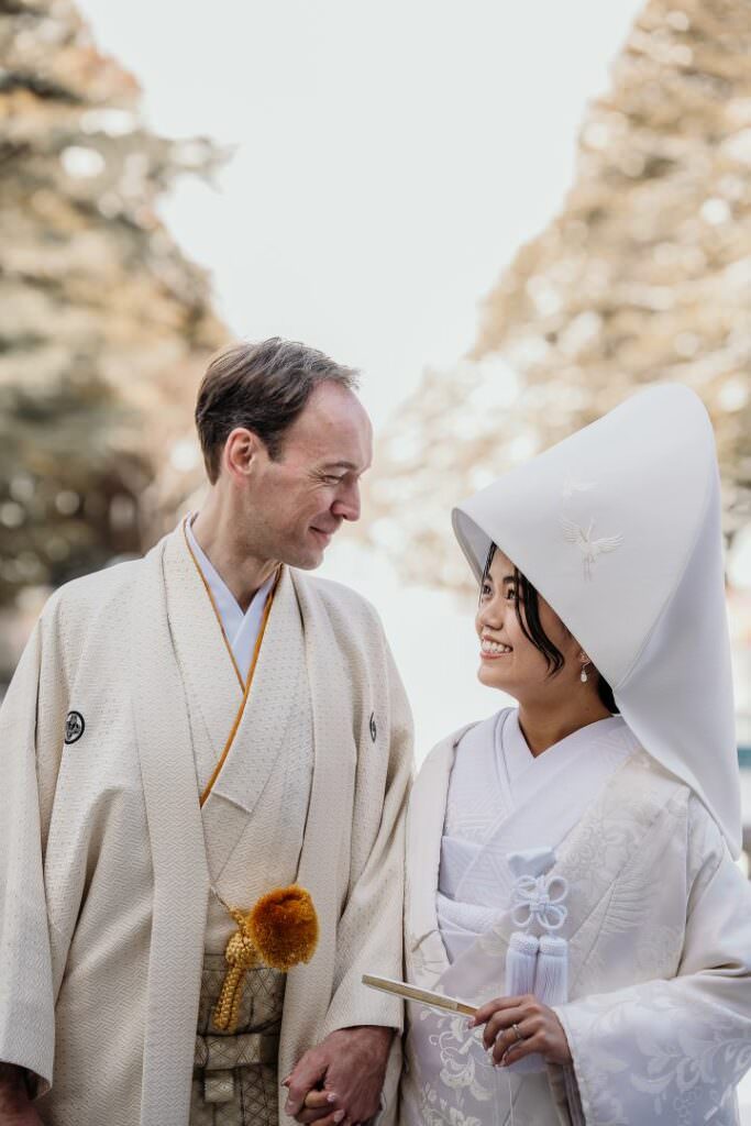 Elegant international couple walking through the snow during their refined Japanese wedding in Hokkaido.