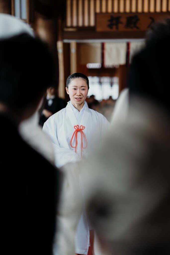 Miko priestess leading the elegant Japanese wedding ceremony inside a Shinto shrine in Hokkaido.