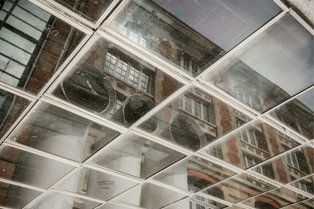 Architectural reflections captured in a geometric glass facade with soft natural light.