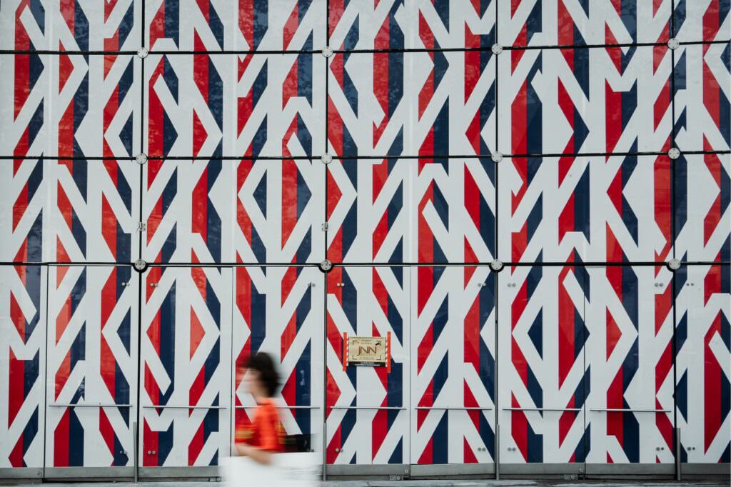 Paris street scene with a bold red and white graphic wall and blurred pedestrian movement.