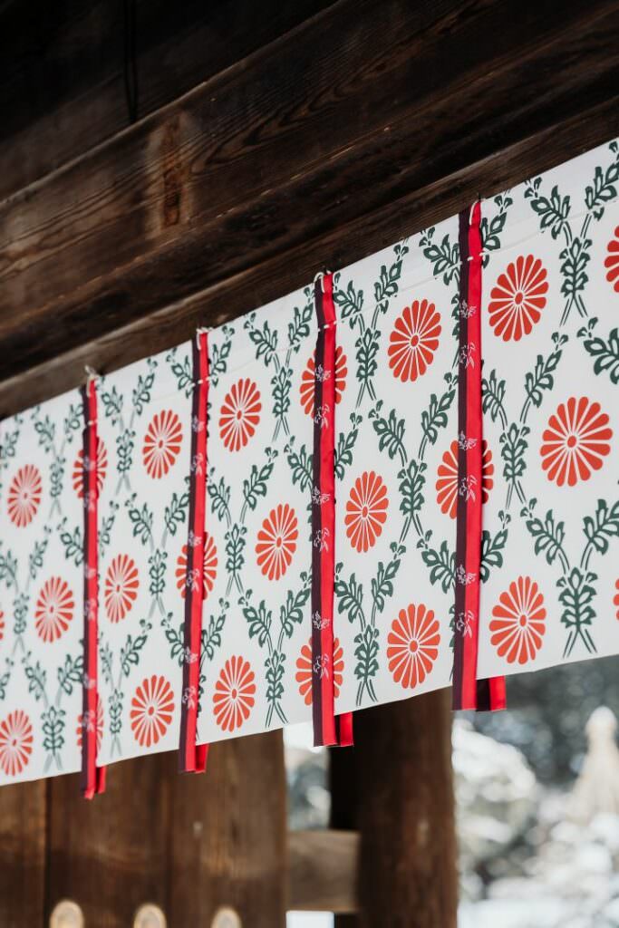 Traditional red and white fabric decorations hanging at Hokkaido Shrine on a winter wedding day.