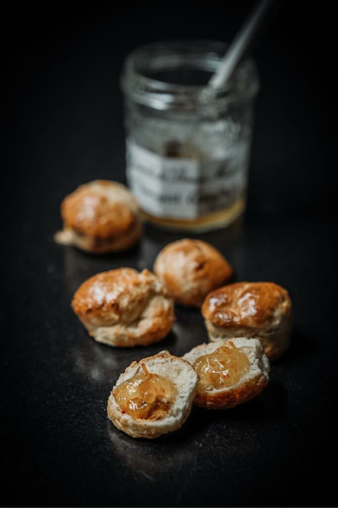 Homemade scones served with orange marmalade, photographed in soft, moody natural light.