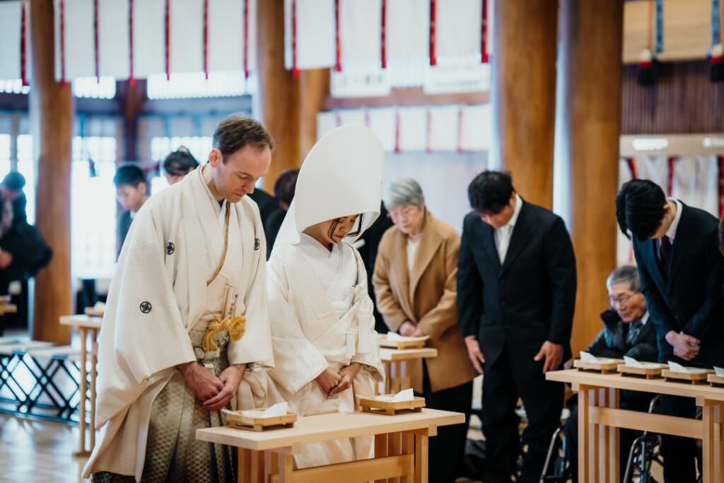 International couple bowing during their refined Japanese Shinto wedding ceremony in Hokkaido.