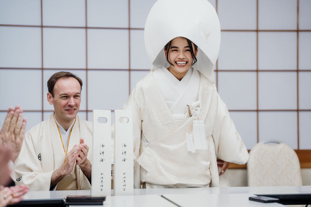 Bride and groom smiling during a formal moment of their Shinto wedding ceremony in Hokkaido.