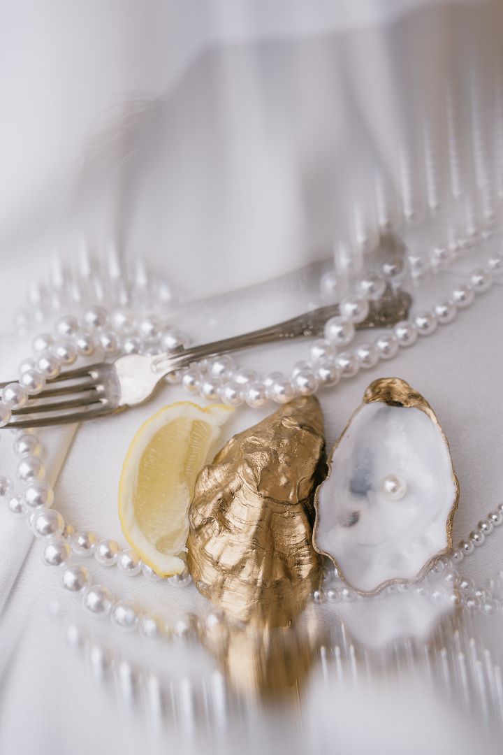 Refined wedding table details with pearls and golden accents, photographed in a luxurious editorial style.