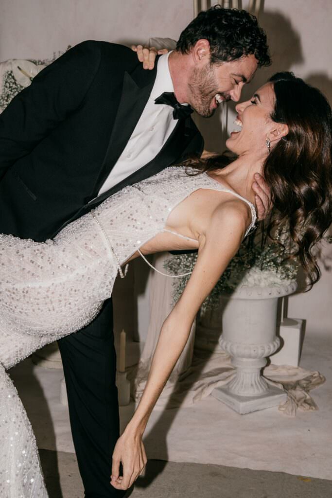 Bride and groom sharing a joyful dance during an elegant wedding celebration.