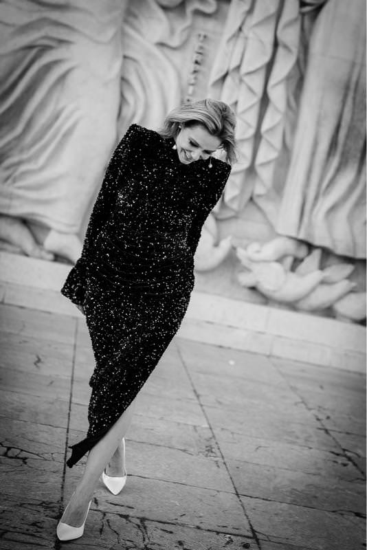 Black-and-white editorial portrait of a woman in a black sequin dress walking at Palais de Tokyo in Paris.