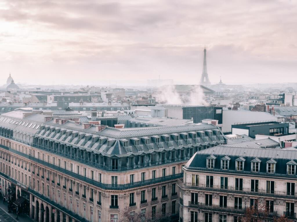 Elegant panoramic view over Paris rooftops with soft morning light and the Eiffel Tower in the distance - refined Parisian atmosphere for sophisticated destination weddings.