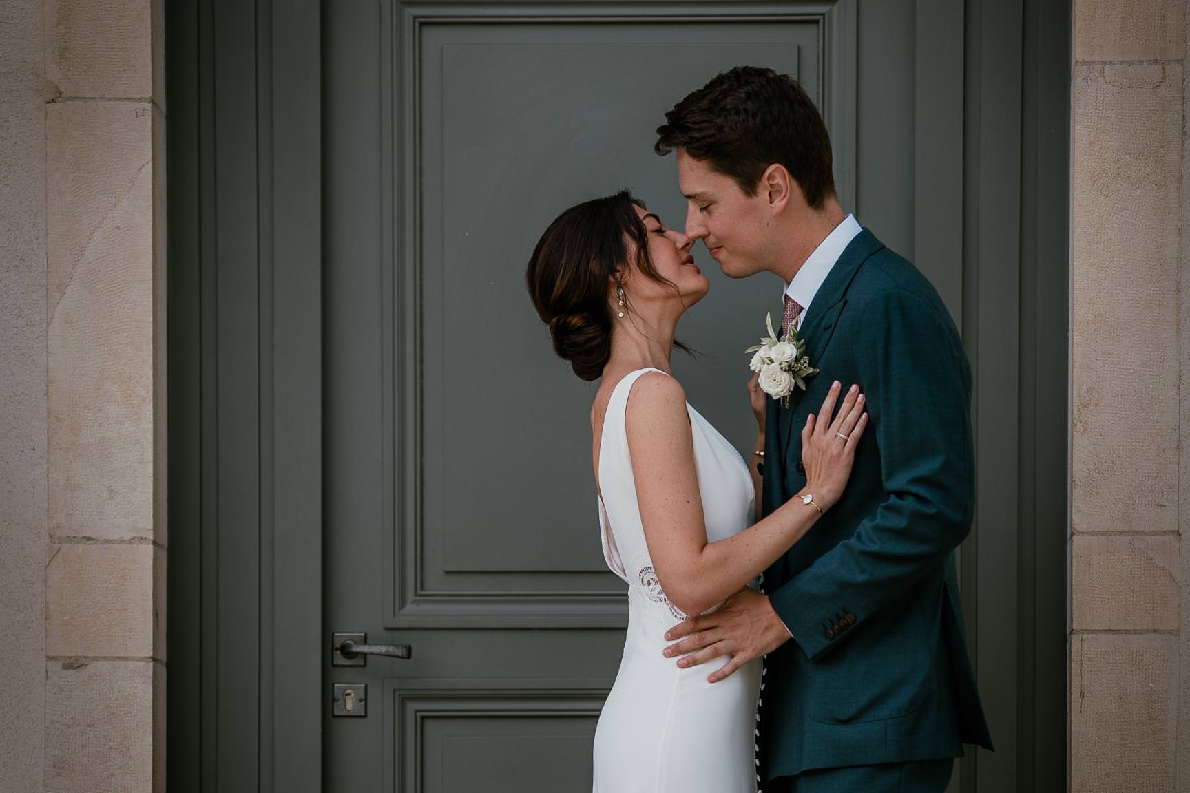 Wedding couple embracing in front of an elegant Parisian doorway.
