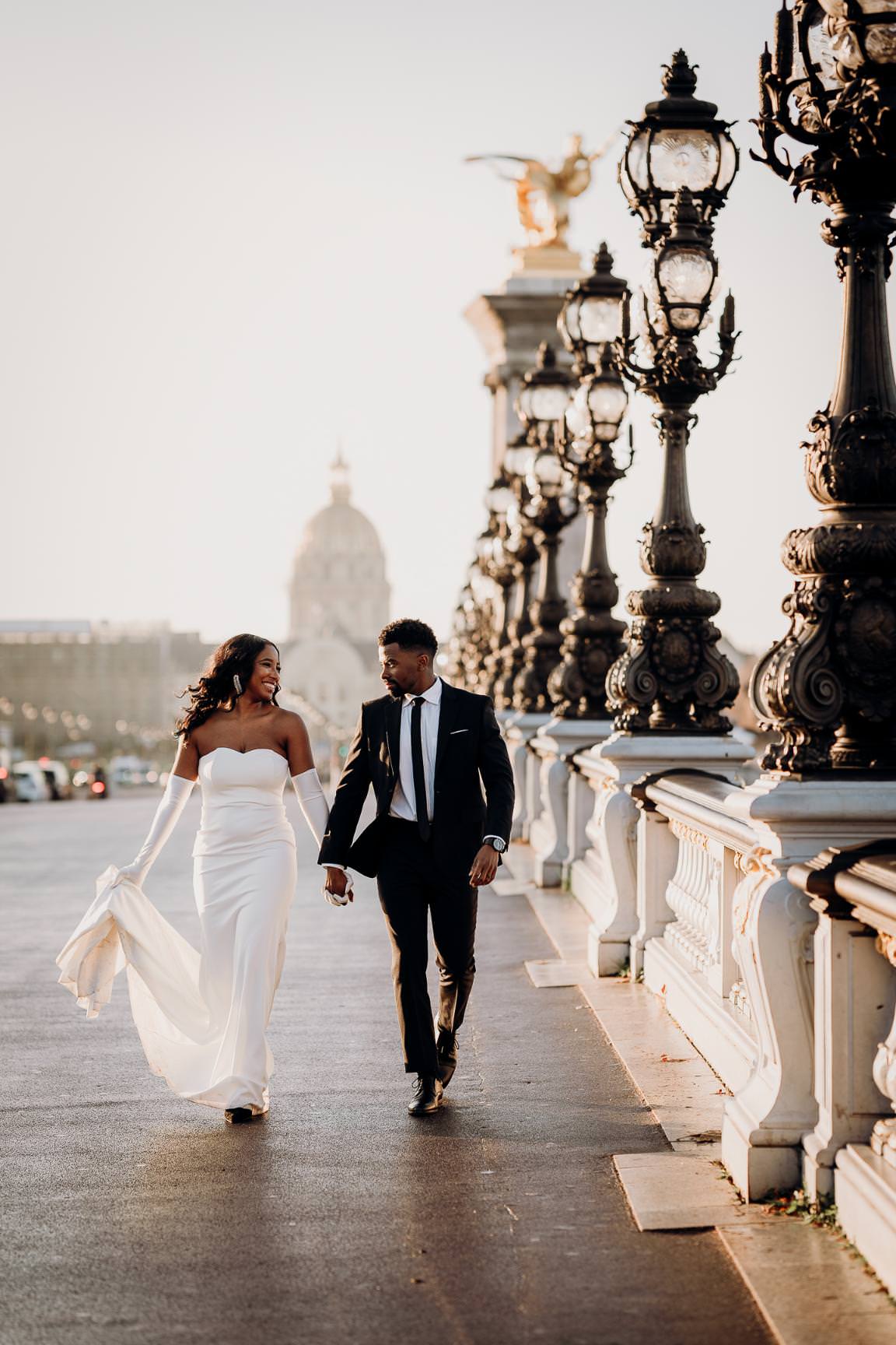 Romantic engagement photo of a couple walking on Pont Alexandre III in Paris.