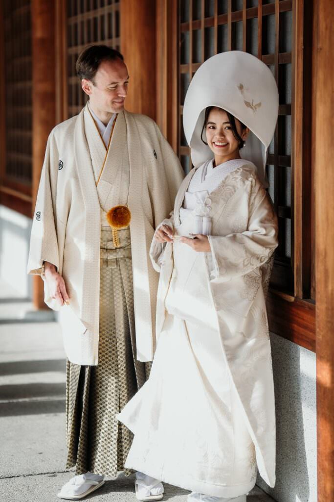 Refined international couple during their elegant Japanese wedding in Hokkaido, standing together in the wooden corridor.