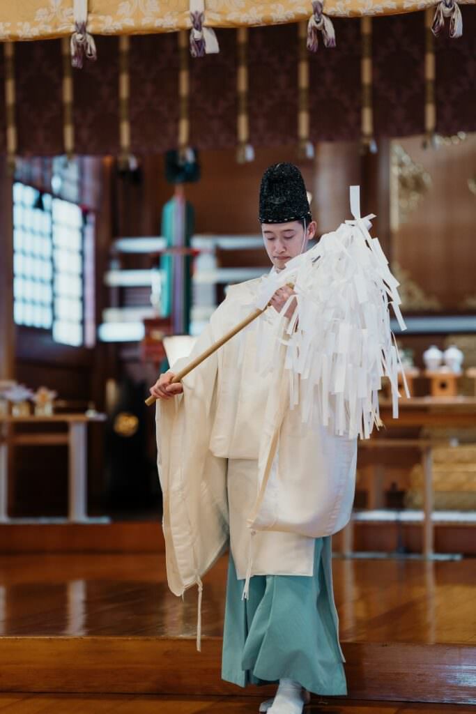 Shinto priest performing a traditional purification ritual during an elegant wedding ceremony in Hokkaido.