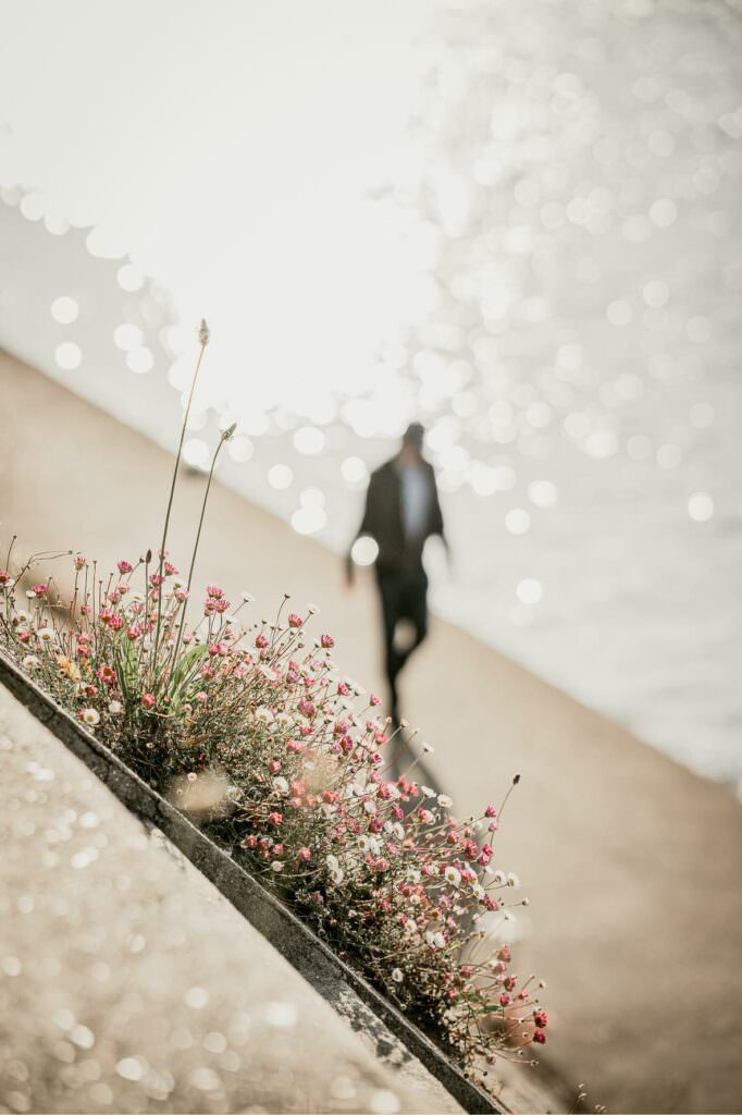 Silhouette of a person walking along the riverside, surrounded by sparkling light on the water.