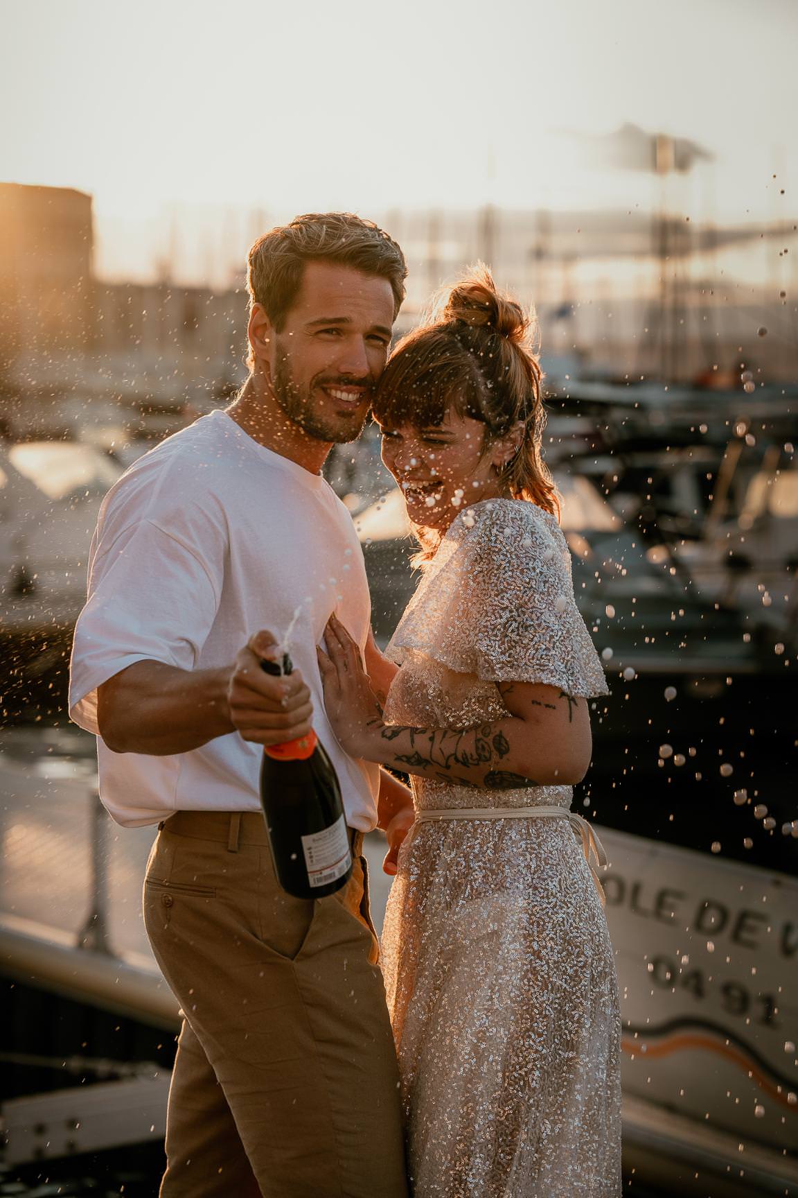 Wedding couple celebrating at the harbor with champagne at sunset.