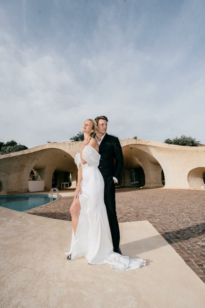 Bride and groom standing together in soft light, framed by modern South of France architecture.