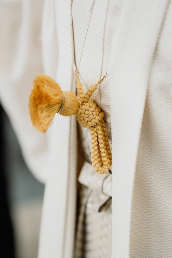 Close-up of a gold tassel detail on traditional Japanese wedding attire worn during a Shinto ceremony.