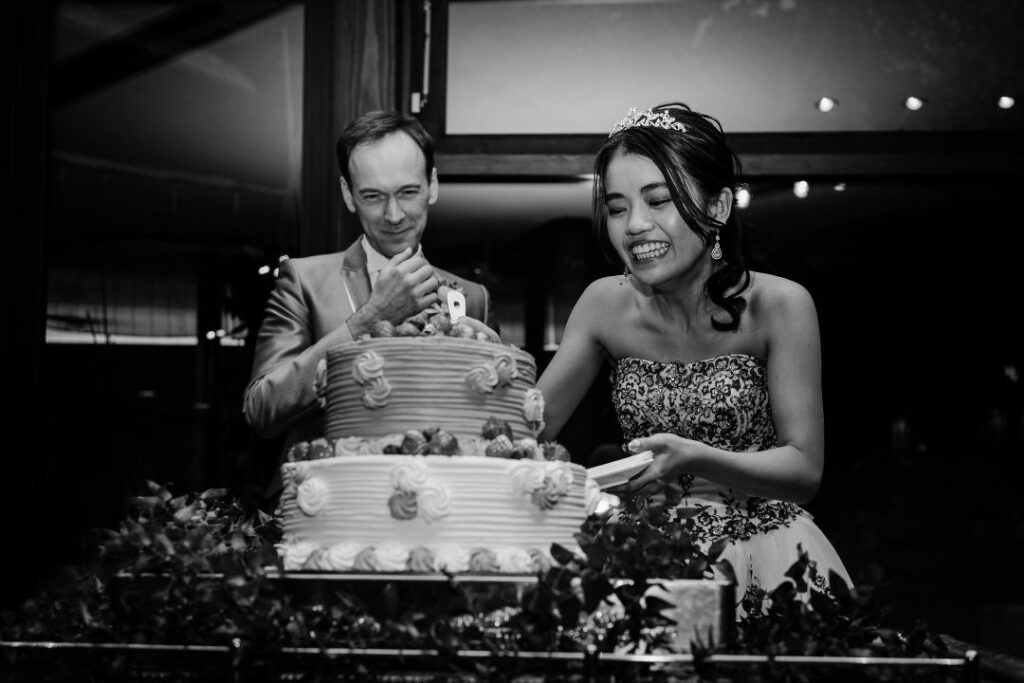 Elegant moment of the bride and groom cutting their wedding cake during a warm and joyful reception in Hokkaido.