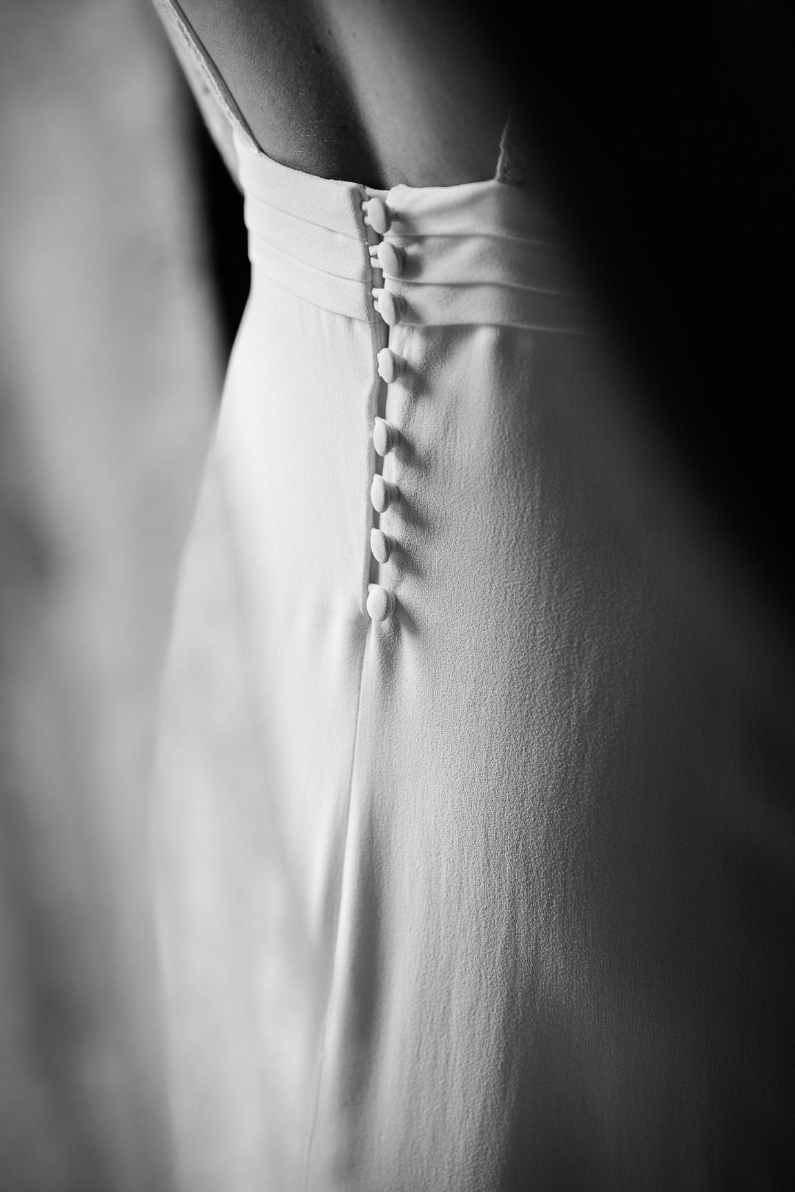 Close-up detail of a wedding dress with delicate buttons down the back.