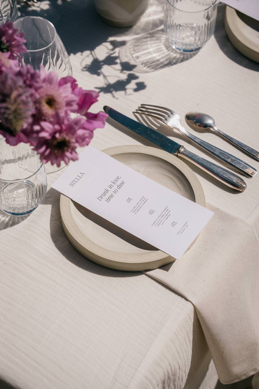 Elegant wedding table flatlay with floral arrangement, menu, and refined tableware.