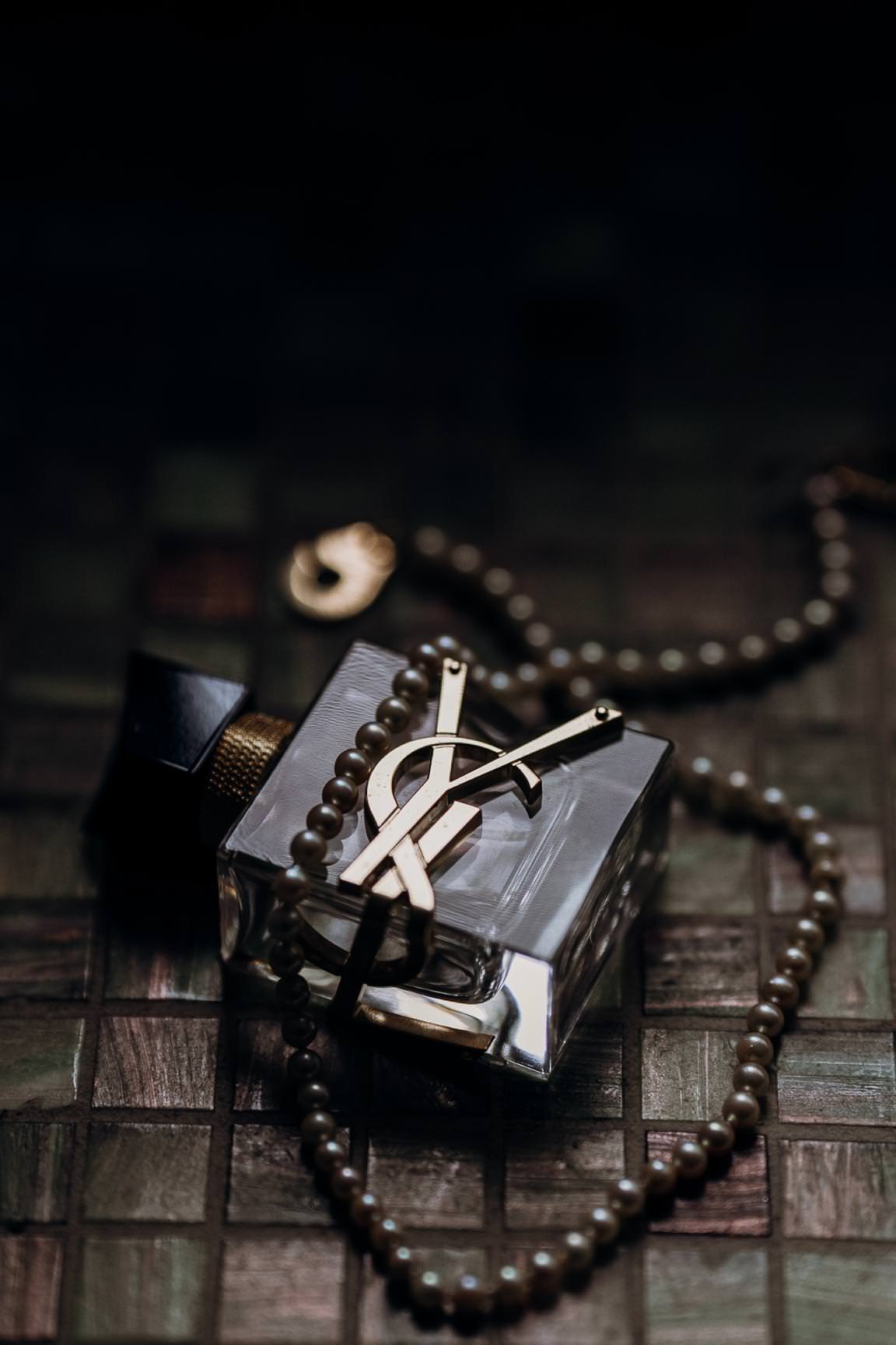 Refined wedding flatlay with perfume and elegant accessories on a textured background.