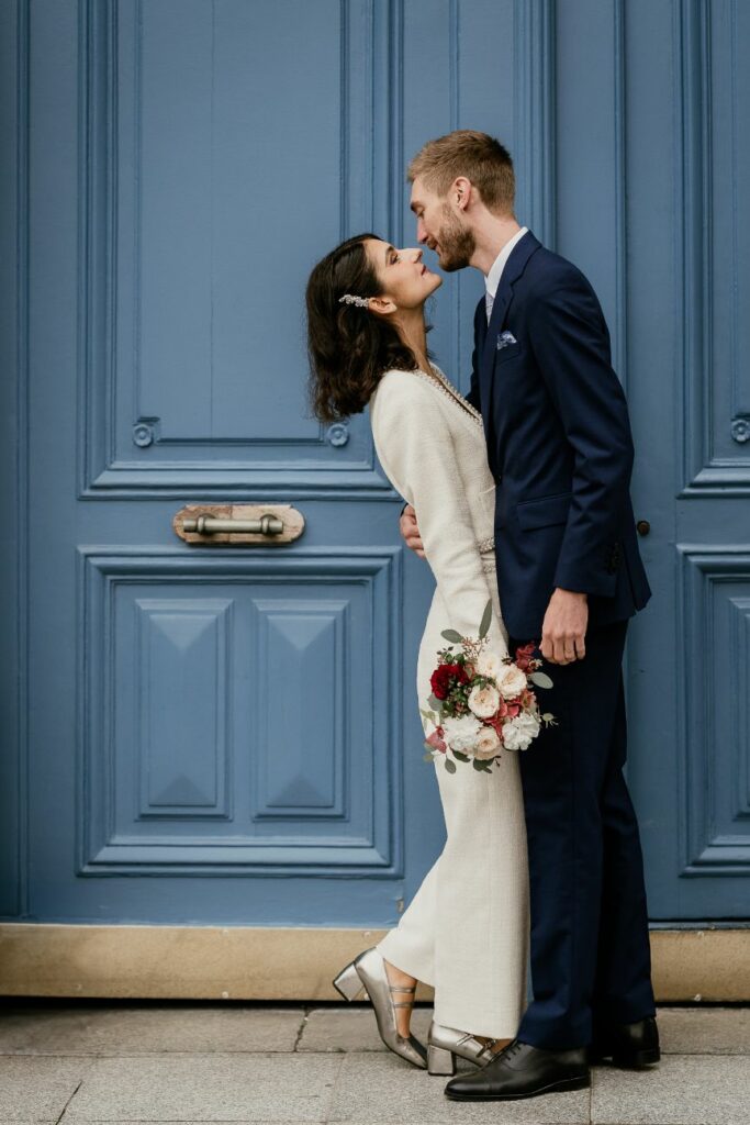 Bride and groom kissing in front of a blue Parisian door