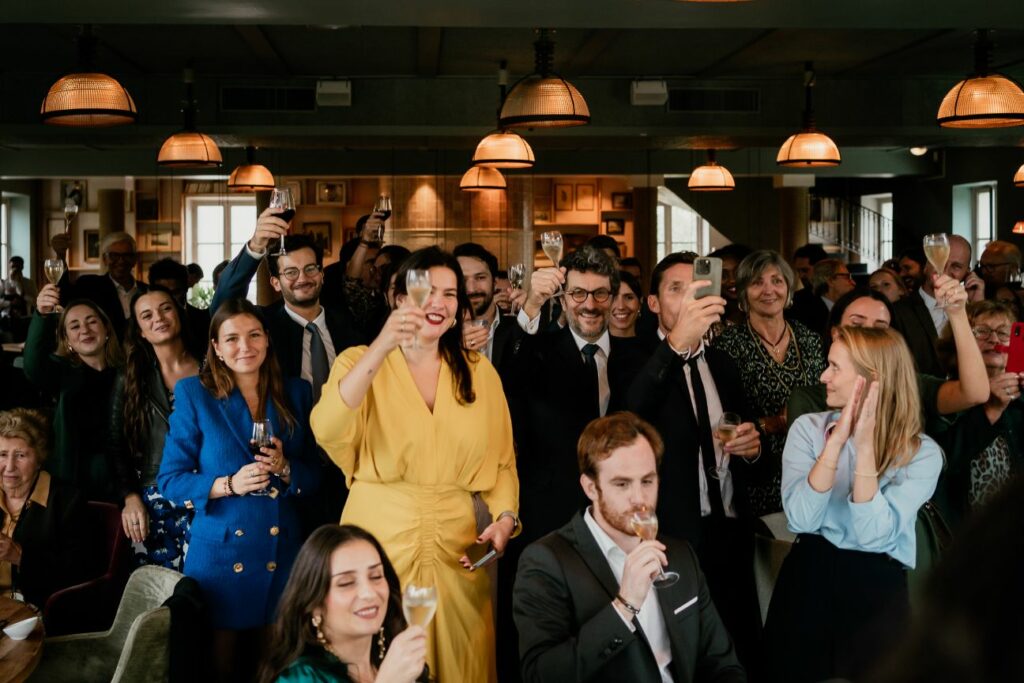 Guests raising their glasses during a relaxed wedding celebration by the river near Paris
